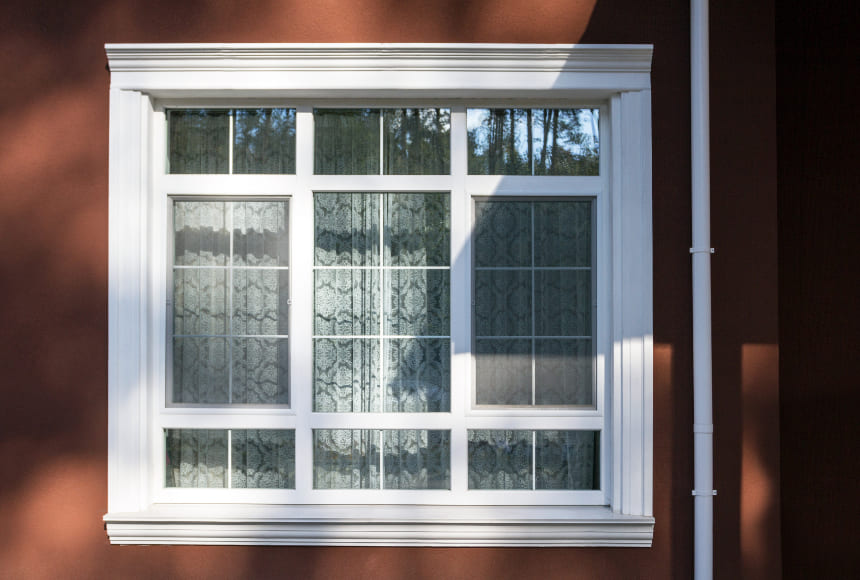 Sprossenfenster aus Kunststoff in rotem Haus mit Sprossen im Scheibenzwischenraum